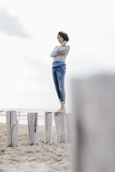 Frau steht auf einem Holzpfahl am Strand - KNSF02621