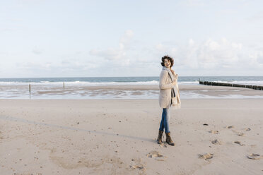 Happy woman standing on the beach - KNSF02628