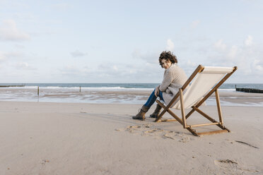 Woman sitting on deckchair on the beach - KNSF02632