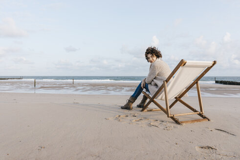 Frau sitzt auf einem Liegestuhl am Strand - KNSF02632