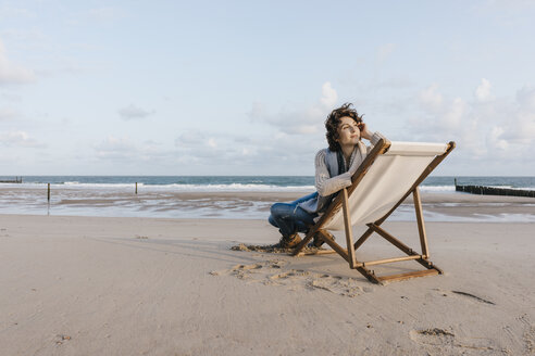 Frau sitzt auf einem Liegestuhl am Strand - KNSF02633