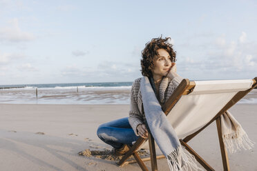 Woman sitting on deckchair on the beach - KNSF02634