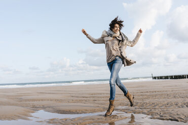 Happy woman running on the beach - KNSF02643