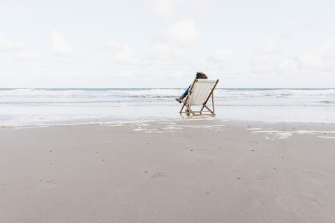 Woman sitting on deckchair on the beach stock photo