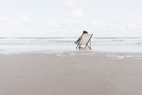 Frau sitzt auf einem Liegestuhl am Strand - KNSF02652