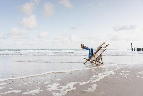 Frau sitzt auf einem Liegestuhl am Strand - KNSF02653
