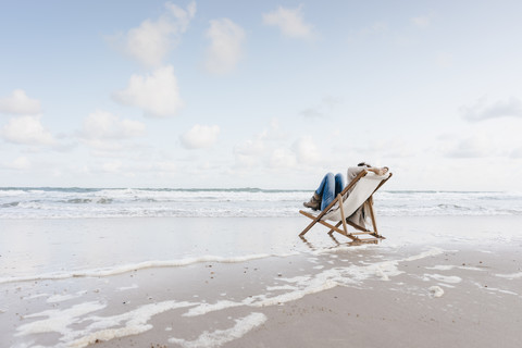 Woman sitting on deckchair on the beach stock photo