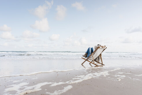 Woman sitting on deckchair on the beach - KNSF02654