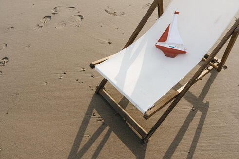 Spielzeugboot im Liegestuhl am Strand - KNSF02658