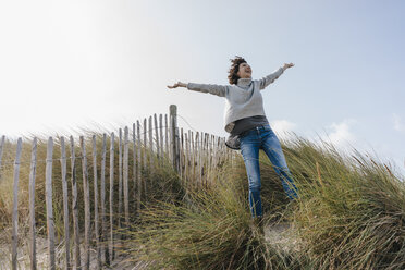 Happy woman standing in beach dune - KNSF02660