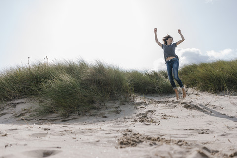 Glückliche Frau springt in Stranddüne, lizenzfreies Stockfoto