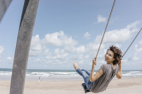 Happy woman on a swing on the beach stock photo