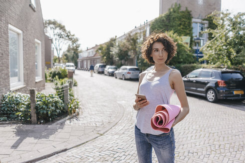 Woman with cell phone and mat on a road - KNSF02679