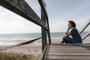 Frau sitzt auf der Strandpromenade am Strand - KNSF02690
