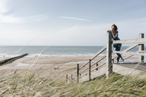 Frau steht auf der Strandpromenade am Strand, lizenzfreies Stockfoto