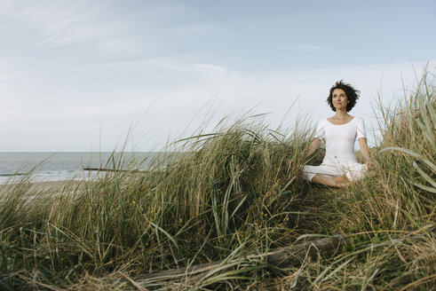 Woman practicing yoga in beach dune - KNSF02695