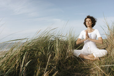 Woman practicing yoga in beach dune - KNSF02696