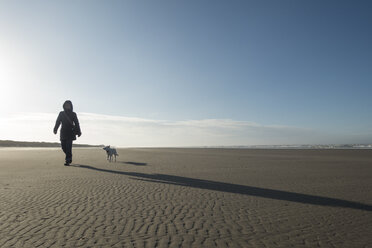 Germany, Lower Saxony, East Frisia, Langeoog, woman with dog on the beach - JATF00971
