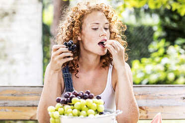 Portrait of redheaded young woman eating grapes - FMKF04422