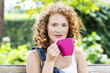 Porträt einer rothaarigen jungen Frau mit rosa Kaffeetasse - FMKF04426