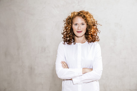 Portrait of redheaded young woman with arms crossed stock photo