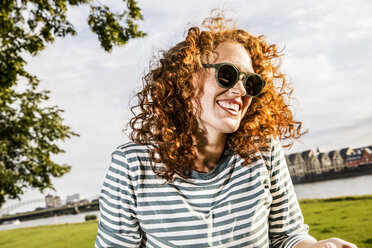 Germany, Cologne, portrait of laughing redheaded young woman wearing sunglasses - FMKF04441