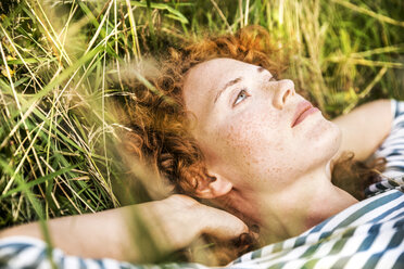 Portrait of young woman relaxing on a meadow - FMKF04446