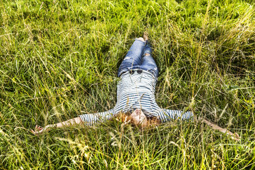 Junge Frau entspannt sich auf einer Wiese - FMKF04447