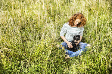 Young woman relaxing on a meadow with her dog - FMKF04451