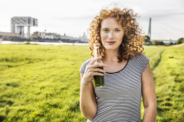 Germany, Cologne, portrait of redheaded young woman with beverage - FMKF04456