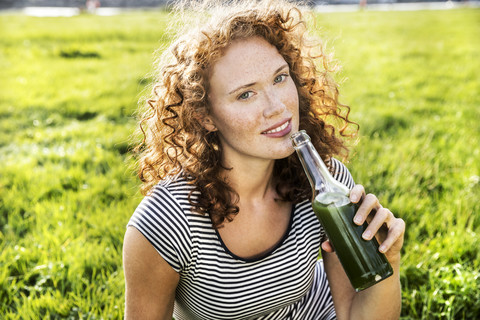 Porträt einer rothaarigen jungen Frau, die ein Getränk genießt, lizenzfreies Stockfoto