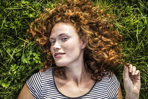 Portrait of smiling young woman lying on a meadow - FMKF04459