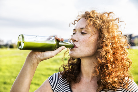 Porträt einer rothaarigen jungen Frau, die ein Getränk trinkt, lizenzfreies Stockfoto