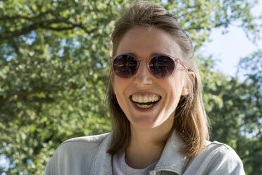 Porträt einer jungen Frau in der Natur, mit Sonnenbrille - LMF00743