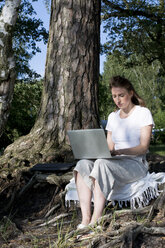 Junge Frau benutzt Laptop im Wald - LMF00752