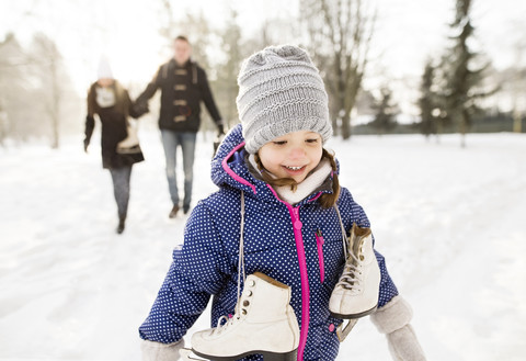 Kleines Mädchen geht mit ihren Eltern Schlittschuhlaufen, lizenzfreies Stockfoto