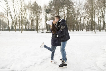 Couple ice skating on a frozen lake, kissing and embracing - HAPF02113