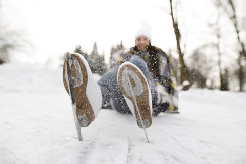 Woman with ice skates lying on snow stock photo