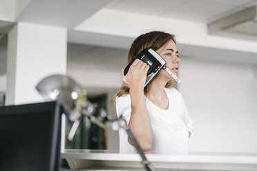 Woman holding a hole punch on her ear - KNSF02712