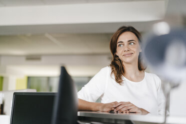 Businesswoman waiting at reception, looking dreamy - KNSF02715