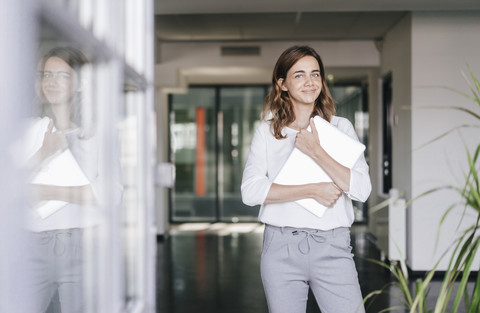 Businesswoman standing in office, holding laptop stock photo