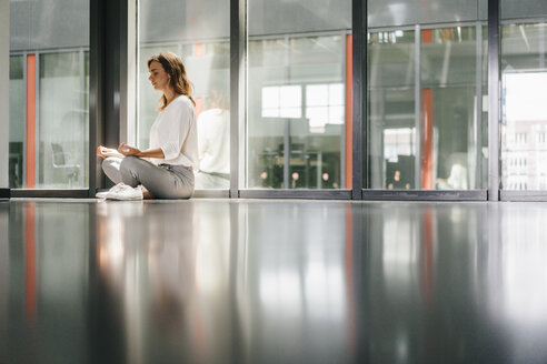 Geschäftsfrau praktiziert Yoga im Büro und meditiert - KNSF02735