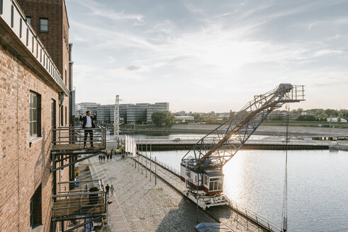 Businessman standing on balcony, flexing muscles - KNSF02736