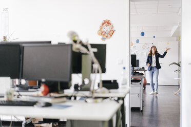 Glückliche Geschäftsfrau, die im Büro mit Bällen jongliert - KNSF02754