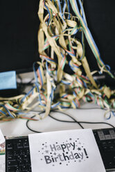 Schreibtisch mit Konfetti und Luftschlangen auf dem Computer nach einer Geburtstagsfeier - KNSF02765