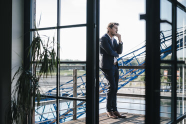 Businessman standing on balcony, looking shocked - KNSF02781