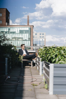 Geschäftsmann entspannt sich in seinem städtischen Dachgarten - KNSF02782