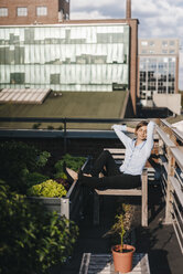 Businesswoman relaxing in his urban rooftop garden - KNSF02793
