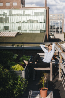 Geschäftsfrau entspannt sich in ihrem städtischen Garten auf dem Dach - KNSF02793