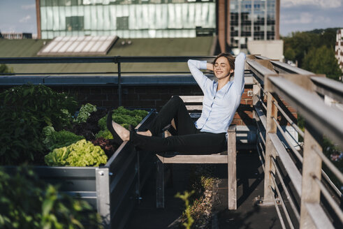Businesswoman relaxing in his urban rooftop garden - KNSF02794